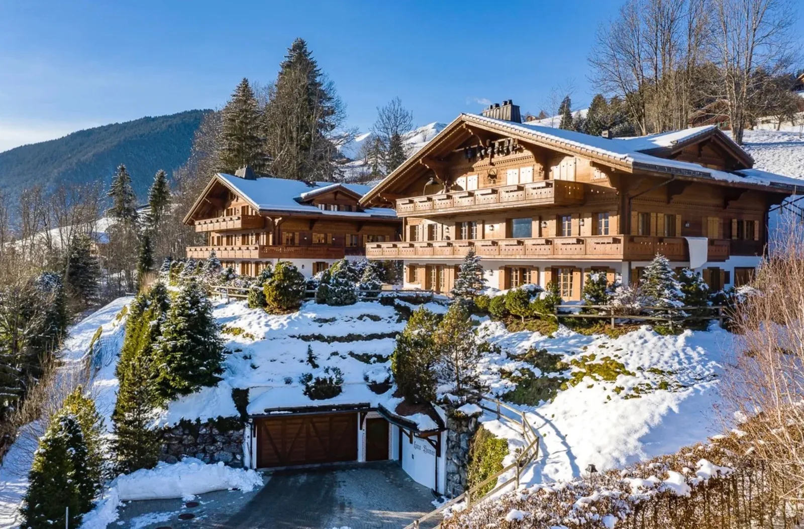 Linked chalets on a snow-covered hillside, their balconies and gables turned towards the valley