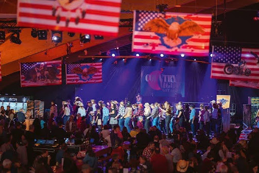 Line dancers on stage beneath American flags at Country Night Gstaad