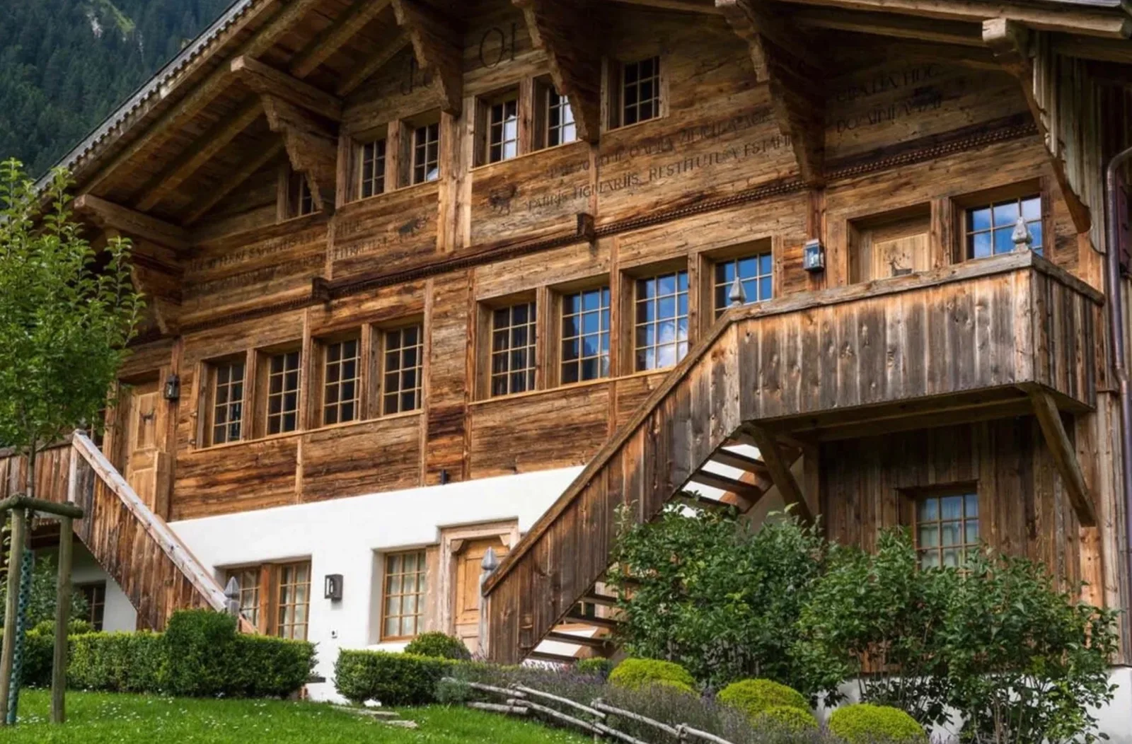 Carved inscriptions running in lines across the beams of a large wooden chalet façade