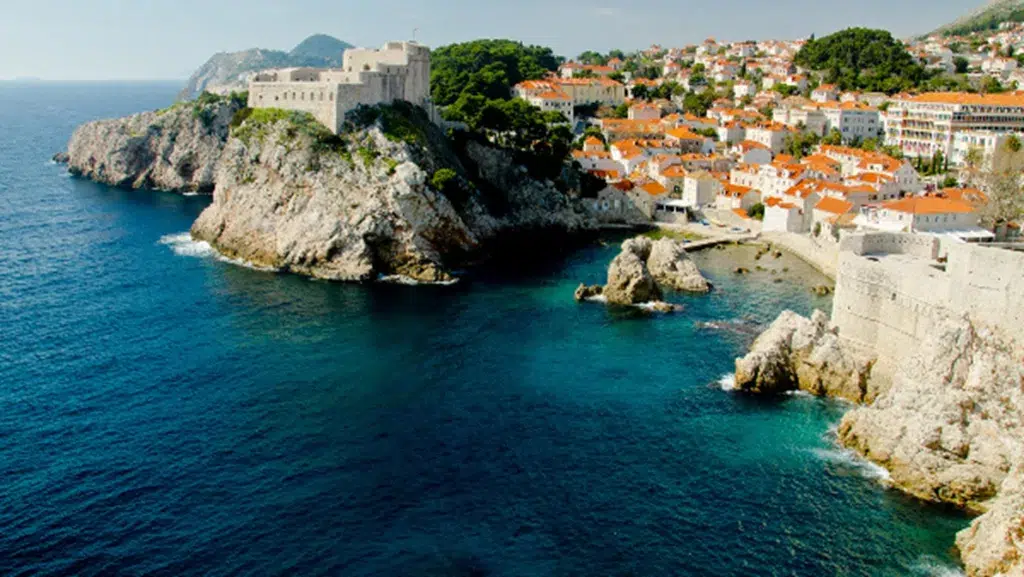 A city on a cliff above water
